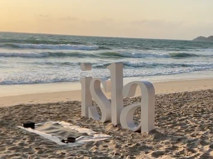 Mats and the studio's letters set up on a resort beach in Koh Samui, waves behind, before a sunrise class