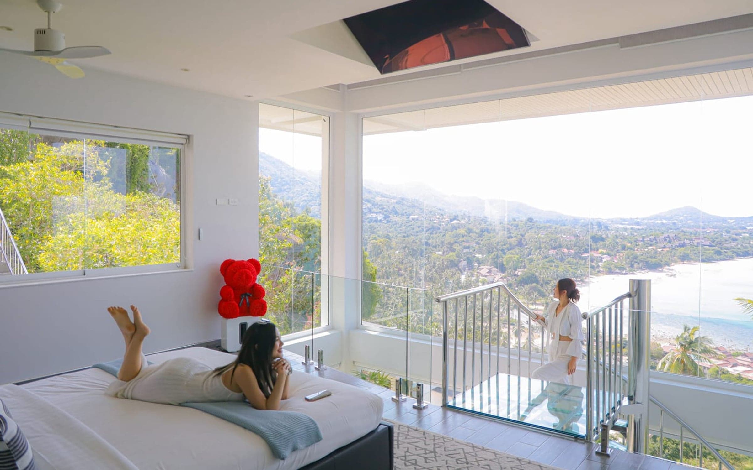 A guest resting in a hillside villa on Koh Samui, the bay through the glass